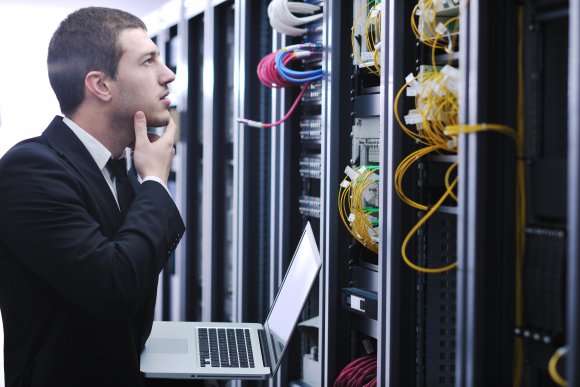 businessman with laptop in network server room